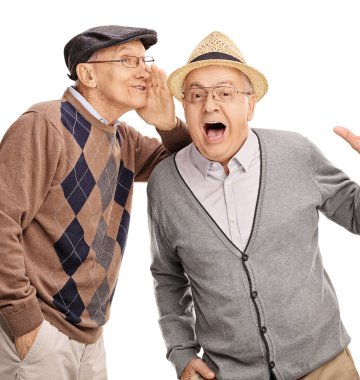Ein Senior flüstert einem anderen etwas ins Ohr.