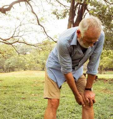 Ein Mann fasst sich an sein Knie währender in der Natur steht