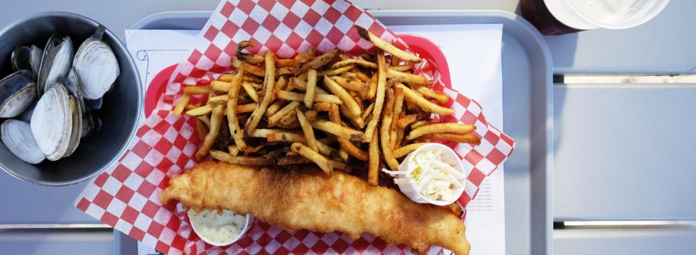 Fisch und Pommes mit Muscheln und einem Getränk serviert