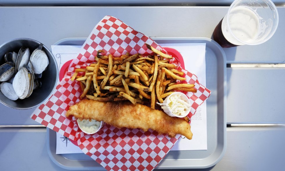 Fisch und Pommes mit Muscheln und einem Getränk serviert