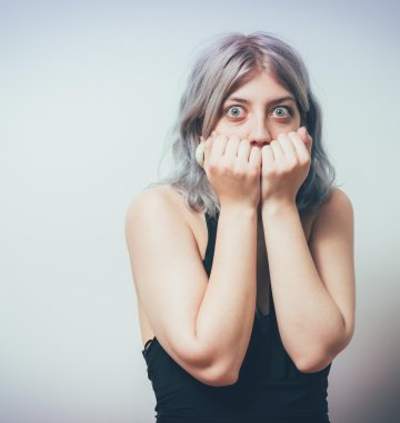 Frau hält sich vor Angst die geballten Fäuste vor ihr Gesicht